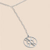 Silver necklace with a round pendant on a beige background